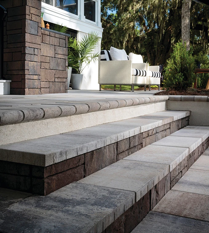 steps-1 Stone steps leading to a patio with outdoor seating, potted plants, and a modern brick exterior.